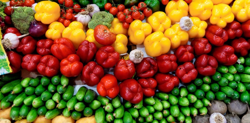 A stand with vegetables such as yellow pepper, beetroot, tomatoes, cucumber, pumpkin, carrots, radish, beetroot, garlic.